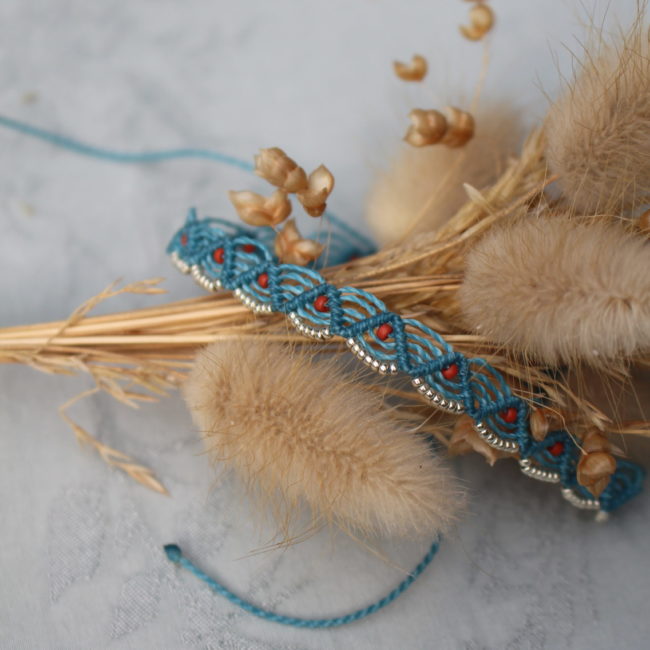 Le bracelet présente un design élégant et bohème, avec une corde bleu tressée en un motif complexe.