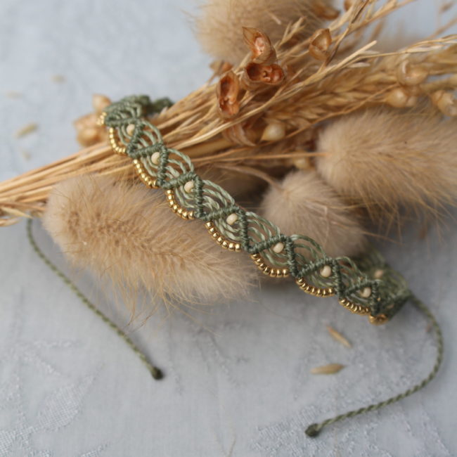 Le bracelet présente un design élégant et bohème, avec une corde verte tressée en un motif complexe.